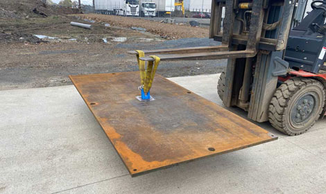 Forklift lifting a steel road plate with a lifting hook